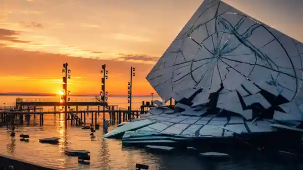 Original OperaAtlas photograph of the Bregenz Seebühne at sunset, with the stage rising from Lake Constance beneath a warm evening sky